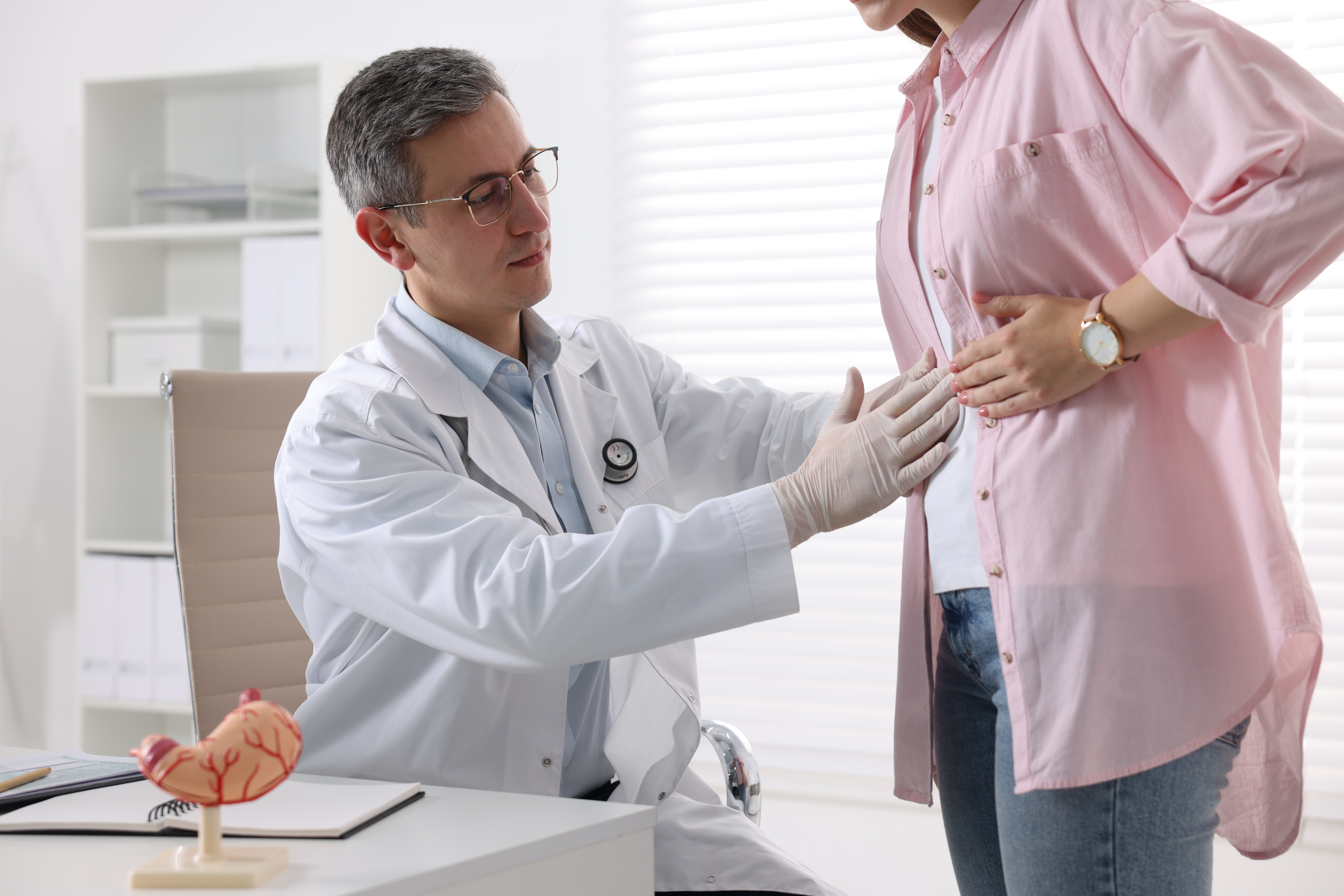 Gastroenterologist examining patient with stomach pain in clinic